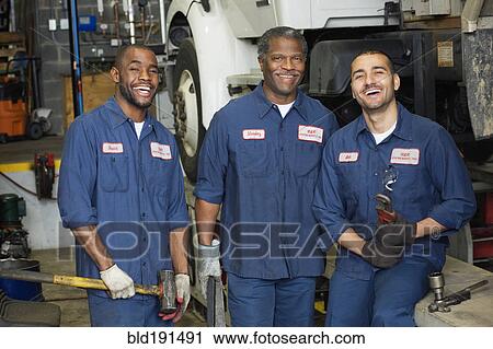Stock Image - Mechanics standing in repair shop. Fotosearch