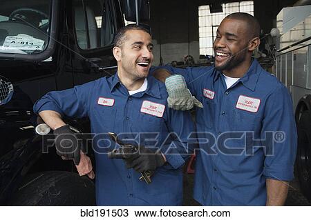 Stock Image - Mechanics working together in repair shop. Fotosearch