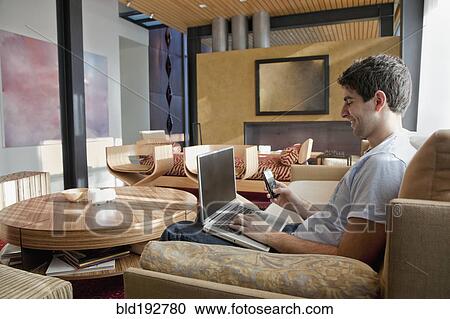 Stock Image - Middle Eastern man using laptop and cell phone. Fotosearch