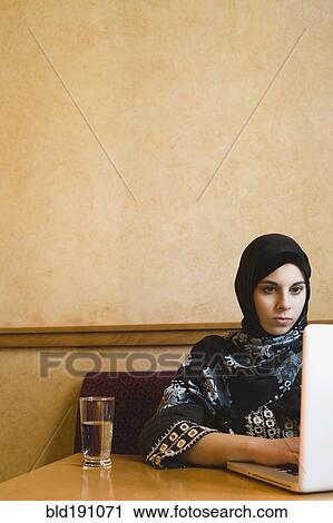 Middle Eastern teenager in headscarf using laptop View Large Photo Image Stock Image - Middle Eastern teenager in headscarf using laptop. Fotosearch