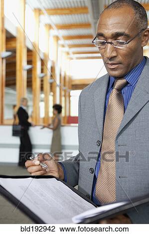 Stock Image - Mixed businessman looking at paperwork. Fotosearch