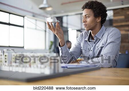 Stock Photo - Mixed race architect examining architectural model in office. Fotosearch