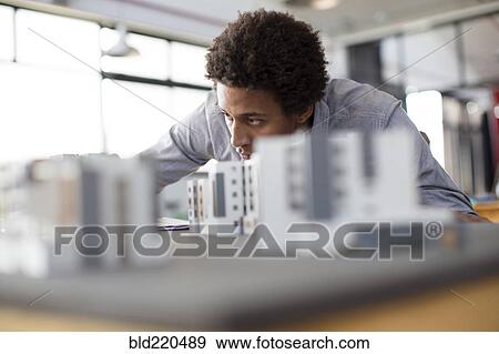 Stock Photo - Mixed race architect examining architectural model in office. Fotosearch