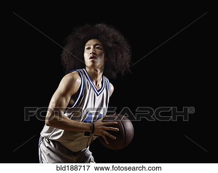 Stock Photo - Mixed race basketball player holding basketball. Fotosearch