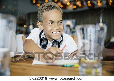 Stock Photo - Mixed race boy coloring at restaurant table. Fotosearch