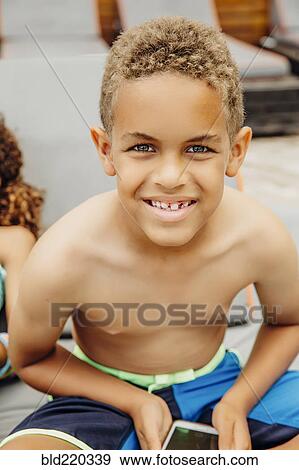 Stock Photo - Mixed race boy holding cell phone on patio. Fotosearch