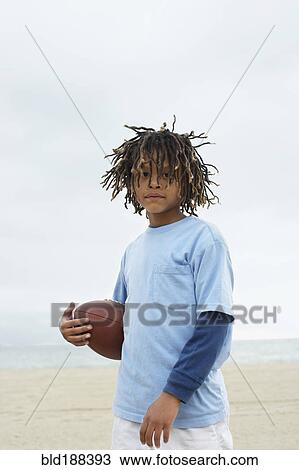 Stock Image - Mixed Race boy holding football. Fotosearch