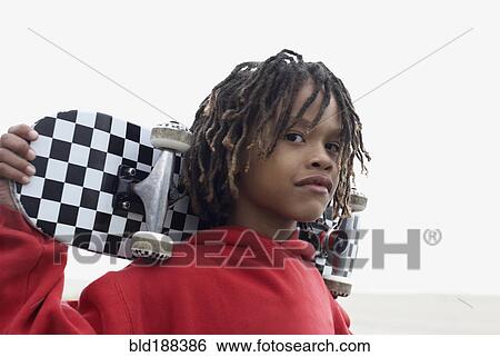 Stock Photograph - Mixed Race boy holding skateboard. Fotosearch