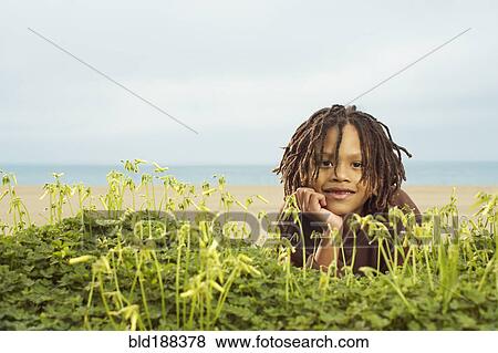 Stock Photo - Mixed Race boy laying in plants. Fotosearch