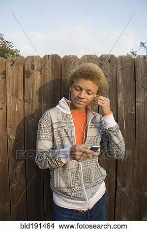 Picture - Mixed race boy listening to mp3 player. Fotosearch