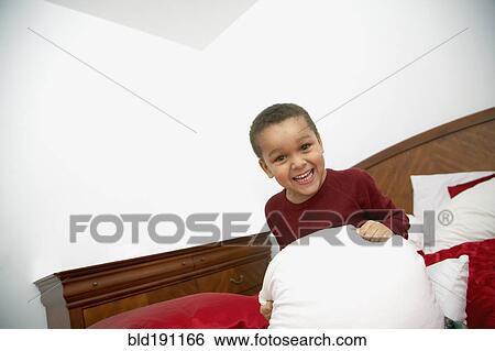 Stock Photograph - Mixed race boy playing on bed. Fotosearch