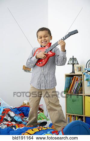 Picture - Mixed race boy playing toy guitar. Fotosearch