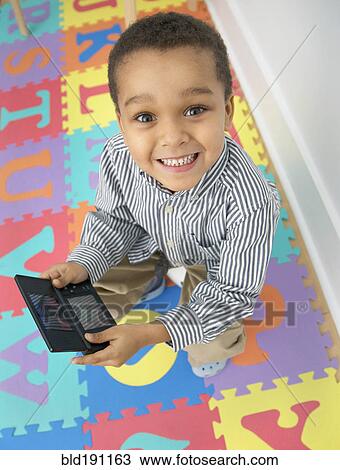 Stock Image - Mixed race boy playing video game. Fotosearch