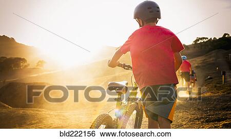 Stock Photograph - Mixed race boy riding dirt bike on track. Fotosearch