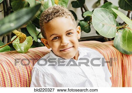 Stock Photo - Mixed race boy smiling on sofa. Fotosearch