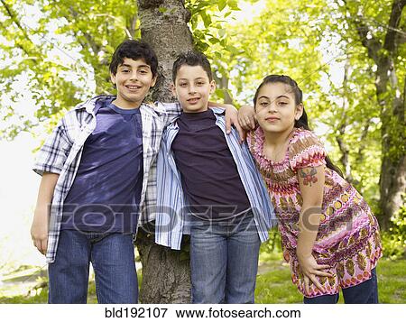 Stock Photo - Mixed race boys and girl hugging in front of tree. Fotosearch
