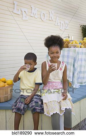 Stock Image - Mixed race brother and sister drinking lemonade. Fotosearch
