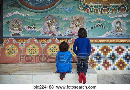 Stock Photo - Mixed Race brothers kneeling on bench examining wall paintings. Fotosearch