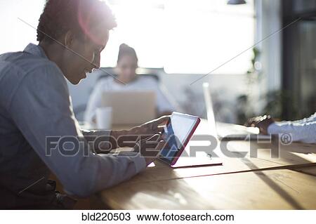 Stock Image - Mixed race business people using technology in office. Fotosearch