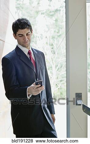 Stock Photo - Mixed race businessman looking at cell phone. Fotosearch