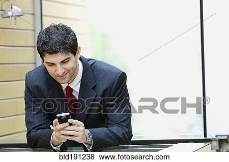 Stock Photo - Mixed race businessman looking at cell phone. Fotosearch