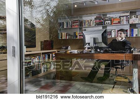 Stock Photograph - Mixed race businessman sitting at desk. Fotosearch