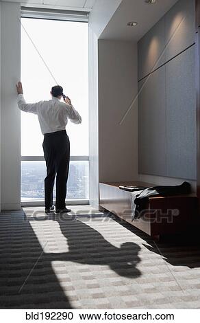 Mixed race businessman talking on cell phone at window View Large Photo Image Stock Image - Mixed race businessman talking on cell phone at window. Fotosearch