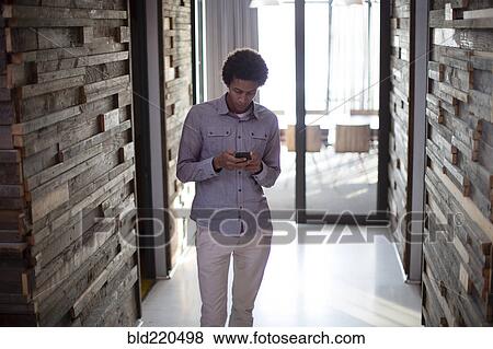 Mixed race businessman using cell phone in hallway View Large Photo Image Stock Photo - Mixed race businessman using cell phone in hallway. Fotosearch