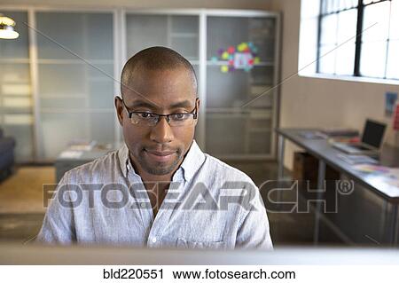 Stock Image - Mixed race businessman using computer in office. Fotosearch