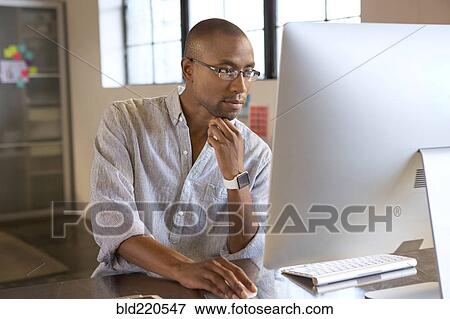Stock Photo - Mixed race businessman using computer in office. Fotosearch