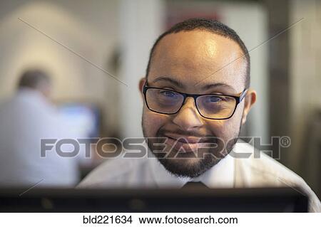 Picture - Mixed race businessman with down syndrome working on computer. Fotosearch
