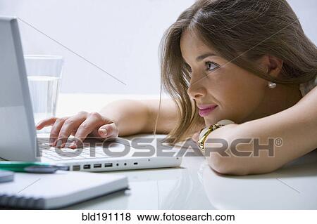 Stock Photo - Mixed race businesswoman laying on desk using laptop. Fotosearch