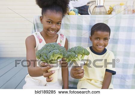 Stock Photography - Mixed race children holding broccoli cones. Fotosearch