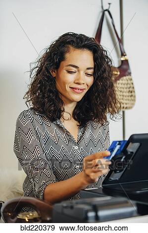 Mixed race clerk swiping credit card at register View Large Photo Image Stock Photo - Mixed race clerk swiping credit card at register. Fotosearch