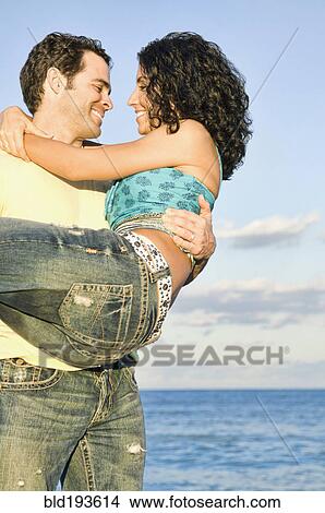 Picture - Mixed race couple playing on beach. Fotosearch