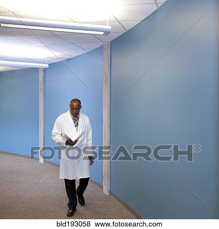 Mixed race doctor walking in hospital with medical chart View Large Photo Image Stock Photo - Mixed race doctor walking in hospital with medical chart. Fotosearch