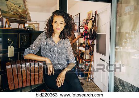Stock Image - Mixed race entrepreneur sitting outside store. Fotosearch