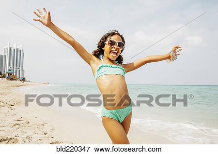 Stock Photo - Mixed race girl cheering on beach. Fotosearch