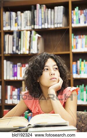 Picture - Mixed race girl doing homework in library. Fotosearch
