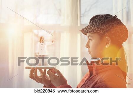 Stock Photography - Mixed race girl examining hologram projection. Fotosearch