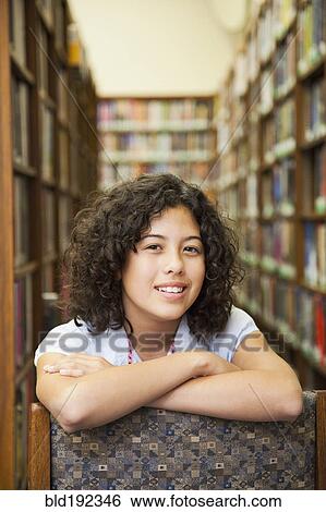Mixed race girl leaning on chair in library View Large Photo Image Stock Photograph - Mixed race girl leaning on chair in library. Fotosearch
