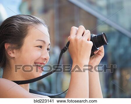 Stock Image - Mixed Race girl photographing outdoors with digital camera. Fotosearch