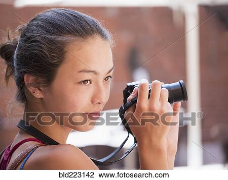 Stock Image - Mixed Race girl photographing outdoors with digital camera. Fotosearch