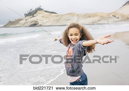 Stock Image - Mixed race girl playing on beach. Fotosearch