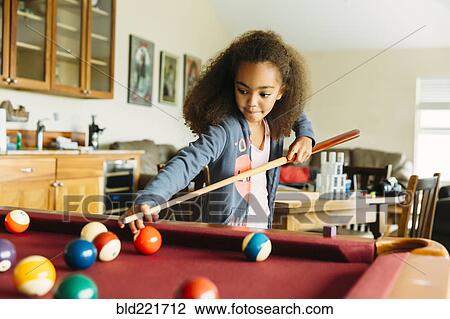 Stock Image - Mixed race girl playing pool. Fotosearch