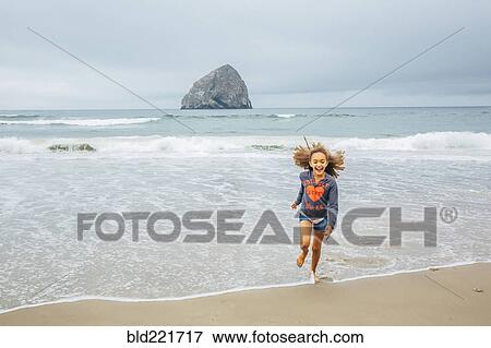Stock Photo - Mixed race girl running on beach. Fotosearch