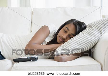 Stock Photograph - Mixed Race girl sleeping on sofa with pillow. Fotosearch