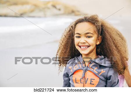 Picture - Mixed race girl smiling on beach. Fotosearch
