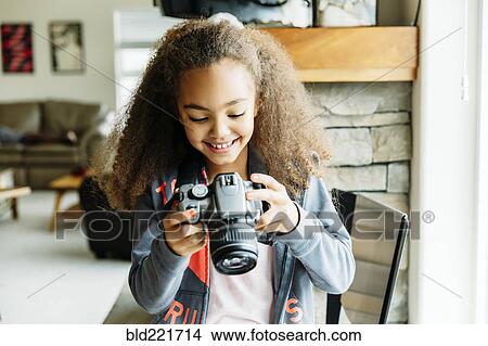 Mixed race girl using camera in living room View Large Photo Image Picture - Mixed race girl using camera in living room. Fotosearch