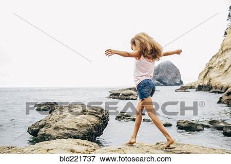Stock Photo - Mixed race girl walking on beach. Fotosearch